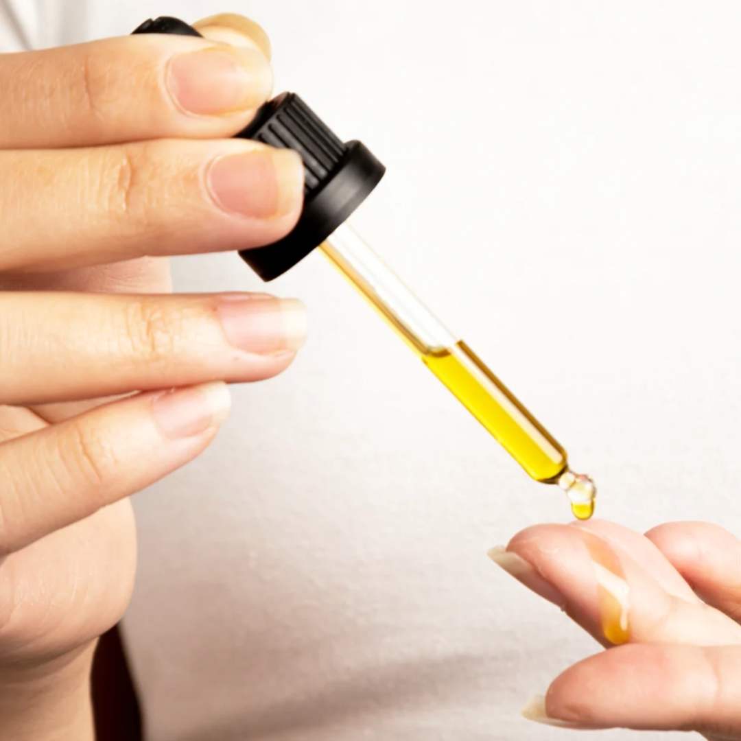 Woman using Clarity Elixir face oil dropper